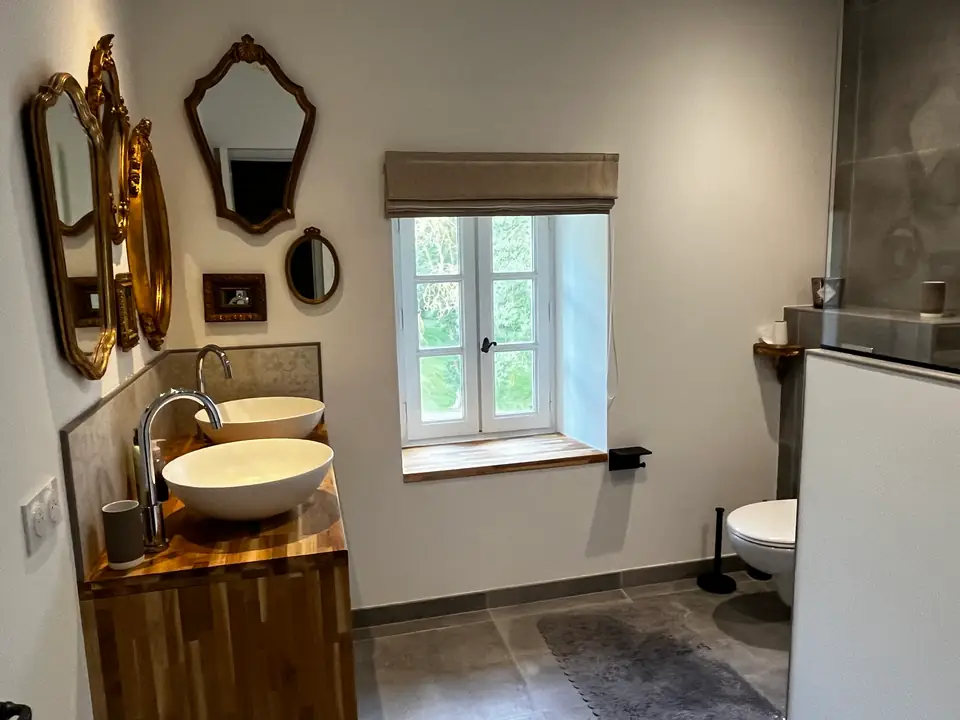 Twee ronde wastafels op een houten kast onder vergulde spiegels.