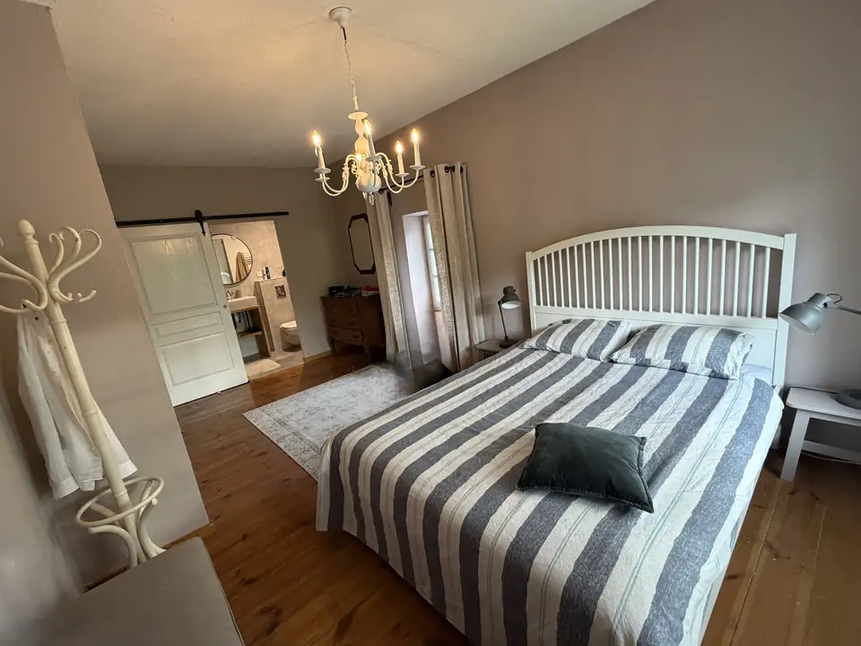 Een slaapkamer met een gestreepte sprei en een kroonluchter.